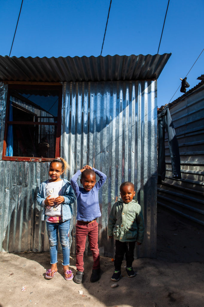 Isabella, her brother and cousin standing next to their new house 